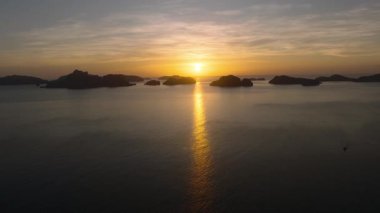 Adaların huzurlu manzarası ve altın günbatımının altında sakin okyanus suyu. El Nido, Palawan. Filipinler.