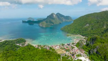 Yoğun bitki örtüsüyle kaplı engebeli kayalıklar denizin canlı renklerine karşı çarpıcı bir tezat oluşturuyor. El Nido, Filipinler.