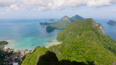 Kıyı şeridinde canlı yeşillik ve kumlu plajların karışımı yer alıyor. Bereketli dağlar berrak mavi denizle buluşur. El Nido, Palawan. Filipinler.
