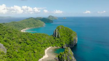 Yeşil ormanlarla çevrili tropikal kumlu bir sahil manzarası. Turkuaz suları olan göller. Cadlao Adası. El Nido. Palawan, Filipinler.