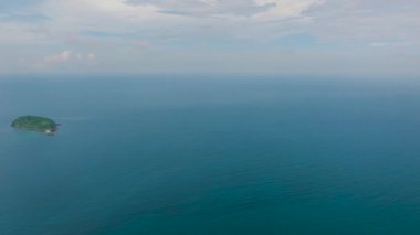Mavi gökyüzü ve bulutların altında adanın etrafındaki sakin deniz yüzeyinin havadan görünüşü. El Nido, Palawan. Filipinler.