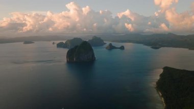 Tropikal adalar ve gün batımı yansımalı kumlu plajlar üzerindeki bulutlu hava. El Nido, Palawan, Filipinler.