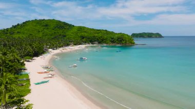 Kumların üzerindeki balıkçı teknelerinin ve turkuaz suların havadan görünüşü. Palmiye ağaçlı Diapela plajı. El Nido, Palawan, Filipinler.
