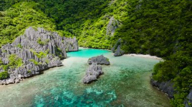 Ubugon koyunun ve turkuaz gölün etrafındaki muhteşem kireçtaşı kayalarının tropikal manzarası. Cadlao Adası. El Nido. Palawan, Filipinler.