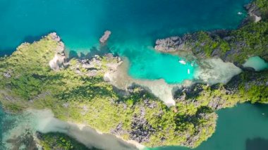 Miniloc Adası 'ndaki gölcüklerin üzerinde güneş yansıması. Turkuaz su üzerinde kano ve turist tekneleri. El Nido, Palawan. Filipinler.
