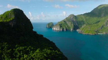 Kireçtaşı oluşumları ve kayalıkları olan adaların insansız hava aracı görüntüsü. Beyaz kumsal ve tekneler. El Nido, Palawan. Filipinler.
