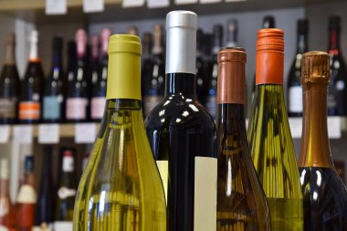 Şarap dükkanında farklı boyutlarda şarap şişeleri var ve eve servis için hazır.