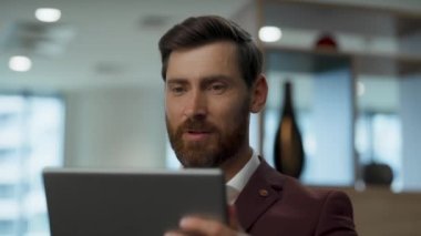 Millennial Man Tablet video konferansı. Arkadaş canlısı iş adamı iş yerinde tek başına açıklama yapıyor. Sakallı girişimci ped bilgisayar aygıtı kullanarak online sohbet ediyor