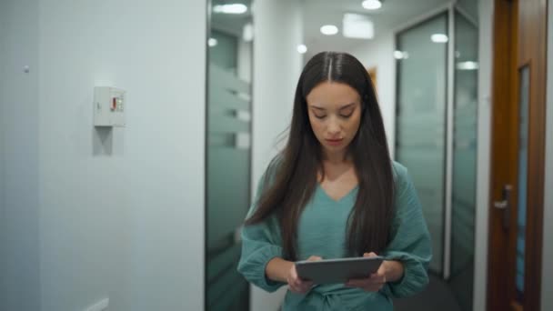 女同事在办公室里浏览平板电脑 忙碌的经理在现代工作场所走过走廊 商界人士在玻璃墙走廊阅读企业数据 专业多样性概念 — 图库视频影像
