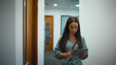 Ofiste çalışan ciddi bir çalışan var. Profesyonel kadın CEO koridorda tablet bilgisayar kullanarak internet taraması yapıyor. Odaklanmış proje yöneticisi yürüyen cam koridor. Şirket yoğun yaşam tarzı kavramı 