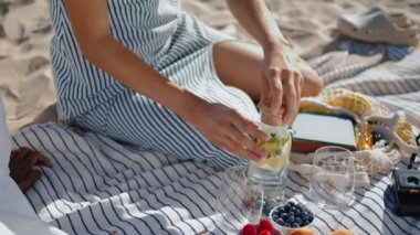 Kapalı eller gün ışığında piknik hazırlıyor. Rahat kız cam yaz plaj sabahına su döktü. Bilinmeyen kaygısız lgbt çifti. Romantik buluşmanın keyfini çıkarıyorlar. Hafta sonu kahvaltısı konsepti. 