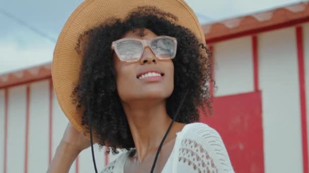 非洲裔美国人在海滨别墅的特写处享受阳光 戴着太阳镜帽的时髦卷曲女孩在海滨休息 微笑的游客在海滨度过暑假 浪漫的情绪概念 — 图库视频影像