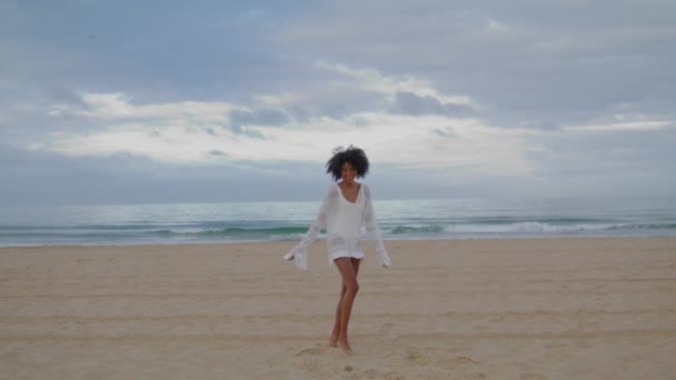 笑顔の女性は海のビーチを実行している 穏やかな海の海岸で砂を投げ踊る陽気な黒い髪の少女 熱帯海岸線の休息を楽しむ幸せなセクシーなアフリカ系アメリカ人女性 気をつけて気分の自由 — ストック動画