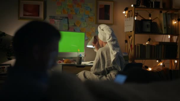 匿名の女性のビデオ通話モックアップPcの閉鎖 緑の画面にスマートフォンを示す介護無料主婦のバックビュー バスローブゴシップ女性話してジェスチャーとともに友人でクロマキーコンピュータ夜 — ストック動画