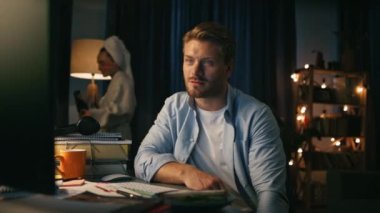 Pozitif adam akşam yakın planda konuşuyor. Evde video dersi almakla meşgul. Bornozlu eş dans ederek eğleniyor. Dikkati kaygısız bir kadın tarafından dağıtılmış, meslektaşlarına el sallayan odaklanmış bir adam.