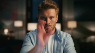 Evde VR oynayan heyecanlı bir oyuncu. Yakın plan çekimde. Fütürist dokunmatik ekranı kullanarak hologram izleyen bir adam. Odaklanmış adam sandviç yiyor, sanal gerçeklik metaevrelerini aşıyor. Yüksek teknoloji konsepti