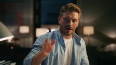 Mutlu adam el sallıyor. Neşeli, uzman, geceleri rahat dairelerde video konferans veriyor. Memlekette serbest çalışan, sohbet eden pozitif bir iş arkadaşı. Gülümseyen adam görüntülü konuşma yapıyor.