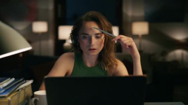 Ev kadını, gece evinde dizüstü bilgisayar kullanmayı düşünüyor. Uzak bir iş yerinde çalışan özenli serbest çalışan bilgisayar yakınlaştırması. Akşam konforlu iç mekanda yazılım mühendisi geliştirme projesi 