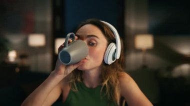 Karanlık yerde kulaklık dinleyen memnun bir kadın. Modern apartman dairesinde serbest dans eden, neşeli bir müzik. Gece dairelerinde kahve içen başarılı bir kız. İnsan duyguları kavramı