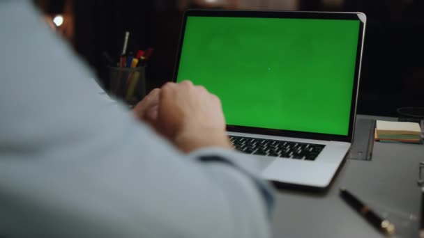 自宅のクローズアップにクロマキーノートパソコンを入力する匿名の男 緑色の画面のコンピュータのリアショットに関する未知のフリーランサーのテキスト情報 モックアップ装置を使った正体不明の男 テクノロジーの概念 — ストック動画