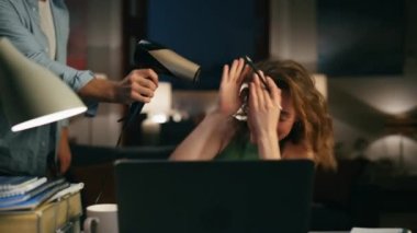 Uzak bir iş yerinde gülen kadını kurutan adam. Komik koca, çalışırken karısının saçını üflüyor. Gülümseyen serbest yazar karanlık odada elleri ile yüzünü gizliyor. Eşini evde ihmal etmeye çalışan kadın