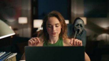 Akıllı kadın geceleri dizüstü bilgisayarı açıklıyor. Serbest çalışan ciddi bir kız, rahat dairelerde videolu görüşme ayarlıyor. Arka planda gizlenmiş çığlık maskeli adam. Cadılar Bayramı konsepti