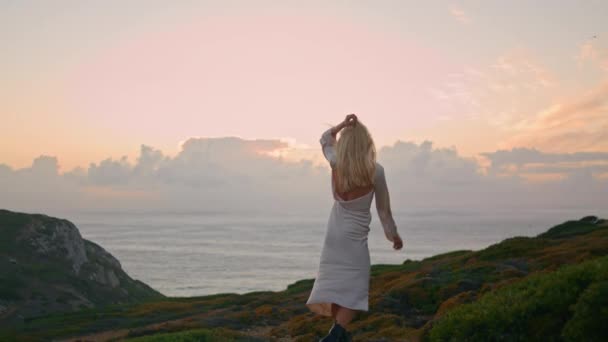 浪漫的女士在黄昏时跳着自然之舞 在绿山环境特写镜头下 积极的女性放松姿势相机 金发姑娘在多风的天气背景下抚摸着头发 — 图库视频影像