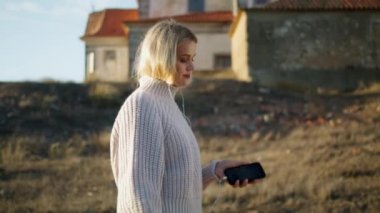 Şato manzaralarında kulaklık takan sakin bir bayan. Sonbahar Tepesi portresinde müzik dinleyen sarışın kadın. Akıllı telefon taşıyan süveter kız kuru sahaya gidiyor. Çayırı tek başına geçen sevimli bir model. 