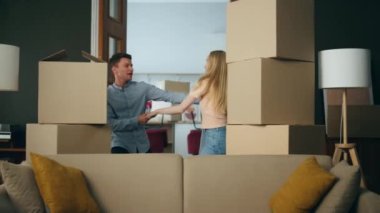 Heyecanlı genç aile yeni eve taşınıp kutular arasında dans ederken iyi eğlenceler. Kendi kiralık mallarıyla eğlenen mutlu çift. Modern daireye taşınmaktan keyif alan pozitif çift..