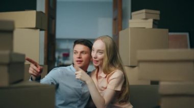 İki mutlu ev sahibi yeni ev oturma odasında oturan iç tasarımı tartışırken paketlenmiş kutular kapanıyor. Genç evli çift modern satın alınmış bir daireye taşınmayı seviyor..