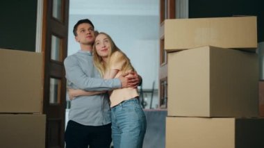 Kutu kutularla dolu yeni bir salona bakan başarılı ev sahipleri. Kiralık dairede genç bir aile sarılıyor. Mutlu çift gülümseyerek kendi modern daireni satın almanın tadını çıkarıyor. Yeniden yerleştirme konsepti.