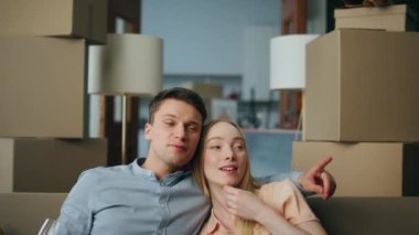 Yeni ev sahipleri oturma odasının iç kısımlarını karton kutularla seyrediyor. Genç ve mutlu bir aile birlikte yeni evi kutluyor kadehlerden şarap içiyor. Yeniden yerleştirme konsepti.