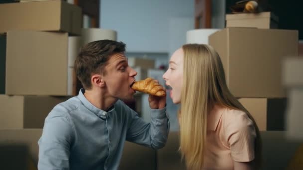 Alegre Joven Pareja Comiendo Croissant Nuevo Apartamento Entre Cajas Cartón — Vídeo de stock