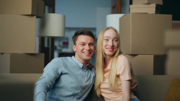年轻夫妇搬到靠近沙发客厅的新公寓居住 快乐的家庭一起讨论室内设计 乐见用抵押贷款搬进新房的一对笑脸 — 图库视频影像