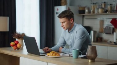 İnternette arama yapan ciddi bir adam rahat bir mutfakta çalışıyor. Genç adam sabah dizüstü bilgisayara bakıp e-postaları kontrol ediyor. Evdeki modern teknoloji not defteri aygıtını kullanmakla meşgul..