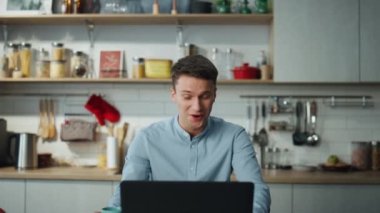Gülümseyen adam dizüstü bilgisayarla konferans videosu çekiyor. Mutfağı kapatıyor. Genç ve çekici bir iş adamı internet kamerasıyla ekiple konuşuyor. Şirket yöneticisinin yakınlaştırma toplantısı var..