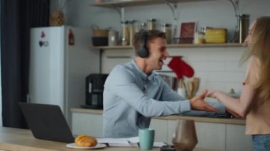 Modern mutfakta dans eden neşeli çift birlikte eğleniyor. Kulaklıklı çekici bir adam genç sarışın karısını daire içine alıyor. Gülümseyen evli çift rahat bir dairede hareket ediyor. Mutlu evlilik kavramı