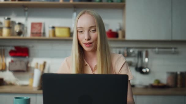 迷人的金发女孩坐在笔记本电脑上在线聊天 坐在厨房桌旁 近距离地喝着新鲜咖啡 快乐的年轻女性微笑着阅读邮件浏览社交网络 漂亮的女士看屏幕 — 图库视频影像
