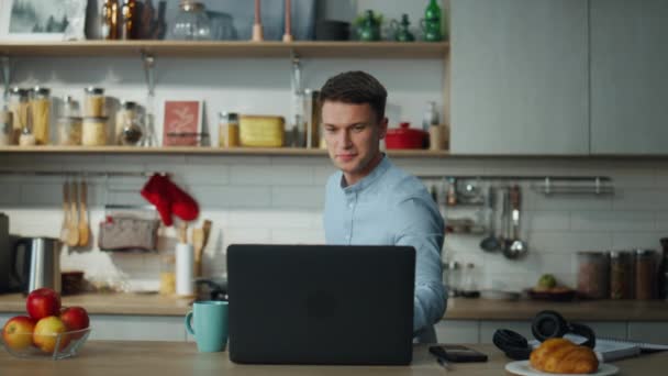 一个积极向上的人正在现代厨房里准备早餐 吸引人的家伙独自做饭使用在线食谱笔记本电脑 微笑的男人做健康的饭菜很开心 — 图库视频影像