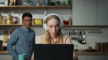 Bilgisayarda internet videosu izleyen sarışın kadın mutfakta kablosuz kulaklık takıyor ve gülümseyen adam bilgisayar ekranına bakıyor. Ciddi kız öğrenci dinleme dersi alıyor. Yakın çekim..