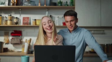 Modern mutfakta dizüstü bilgisayarla konuşan mutlu çift. Çevrimiçi arkadaşlarıyla iletişim kuran neşeli bir aile. Evdeki internet bağlantısıyla konuşan sevimli pozitif çift..