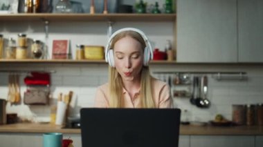 Mutfakta dizüstü bilgisayarla oturmuş kulaklıkla müzik dinleyen rahat bir öğrenci. Evde sosyal ağlara bakarken dans eden çekici sarışın kadın. Şirin bayan gülümsüyor..