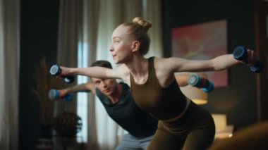 Genç bir aile evde dambıllarla spor yapıyor. Çekici ve sportif bir çift ağırlıkla el sallıyor. Zayıf sarışın kadın, atletik bir adamla kol gücü eğitiyordu. Partnerler birlikte çalışırlar..