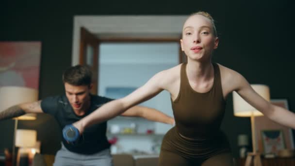 家里有带哑铃的家庭锻炼 快乐的运动女子与身穿运动服的运动男子一起训练手力 适合年轻夫妇一起锻炼身体以获得健康的身体 积极的体育生活方式 — 图库视频影像
