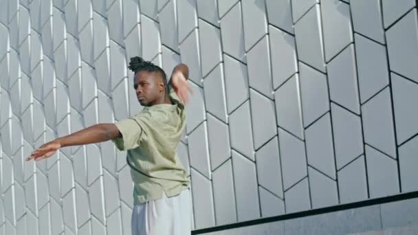 ストリートダンサー都市を閉じる移動します 壁の背景の上で踊るスタイリッシュな黒い髪の男 コンテンポラリー振付を単独で行う芸術家 アフリカ系アメリカ人のパフォーマーは感情的に — ストック動画