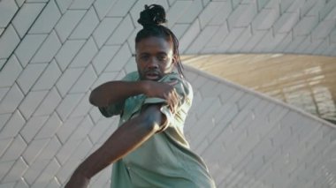 Sokak fotoğrafı çeken serbest dans eden bir dansçı. Açık havada modern dans doğaçlamasını yapan Afrikalı Amerikalı bir adam. Siyah saçlı adam ağır çekimde hareket ediyor. Gençlik kültürü