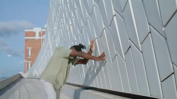 劇的な男は感情スタジアムの閉鎖を表現します 柔軟な演奏者が現代的な動きだけをリハーサルする アフリカ系アメリカ人の男性は抽象的な壁の近くでフリースタイルダンスを見せる 才能ある芸術家が創造的に踊る — ストック動画