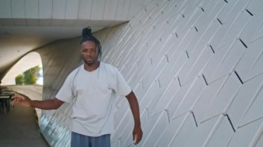 Şehir portresine bakan yaratıcı adam. Modern mimaride ritmik dans eden siyah saçlı genç bir sanatçı. Afrikalı Amerikalı dansçı köprü altında doğaçlama yapıyor. Serbest biçim kavramı