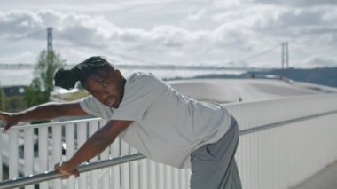 Akrobatik sanatçı, deniz arka planında dans provası yapıyor. Dramatik adam tek başına gerçek duygularını gösteriyor. Metal Köprü 'de Afrikalı Amerikalı dansçı doğaçlaması. Yetenekli sanatçı, yaratıcı şehir serbest stiliyle dans ediyor.