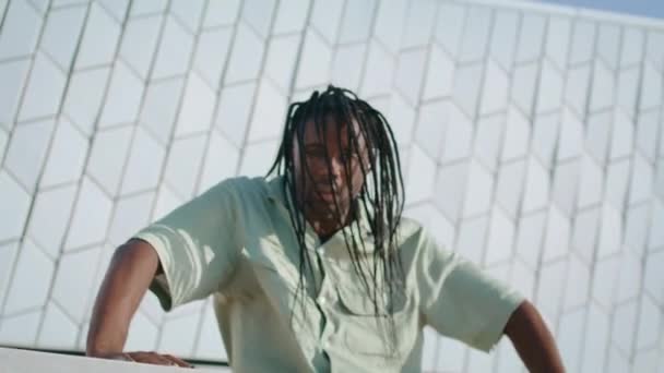 令人毛骨悚然的男人跳舞抽象的墙壁肖像 黑色头发的家伙触摸混凝土建筑在现代地区 非洲裔美国舞蹈家即兴表演当代技巧 演出者看相机 — 图库视频影像